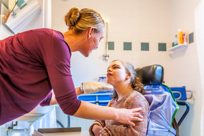 child in a wheelchair being cared for by a special needs nurse